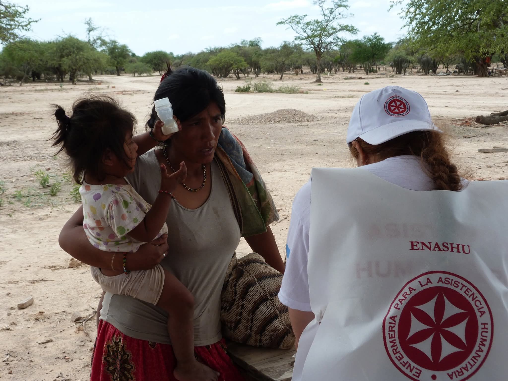 Una voluntaria de ENASHU conversa con una madre y su hija durante una atención en territorio